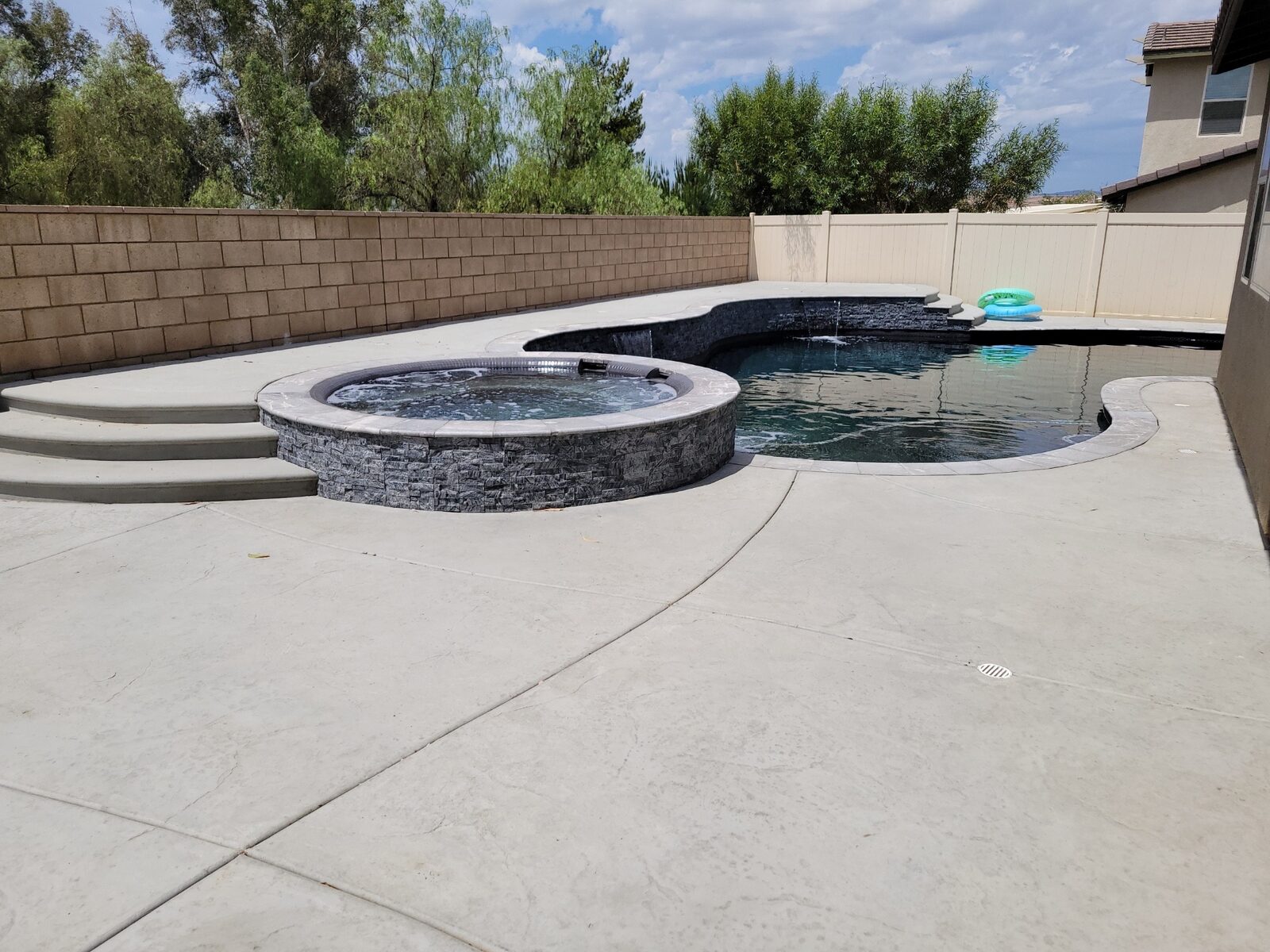 Pool and raised stacked-stone spa with concrete deck