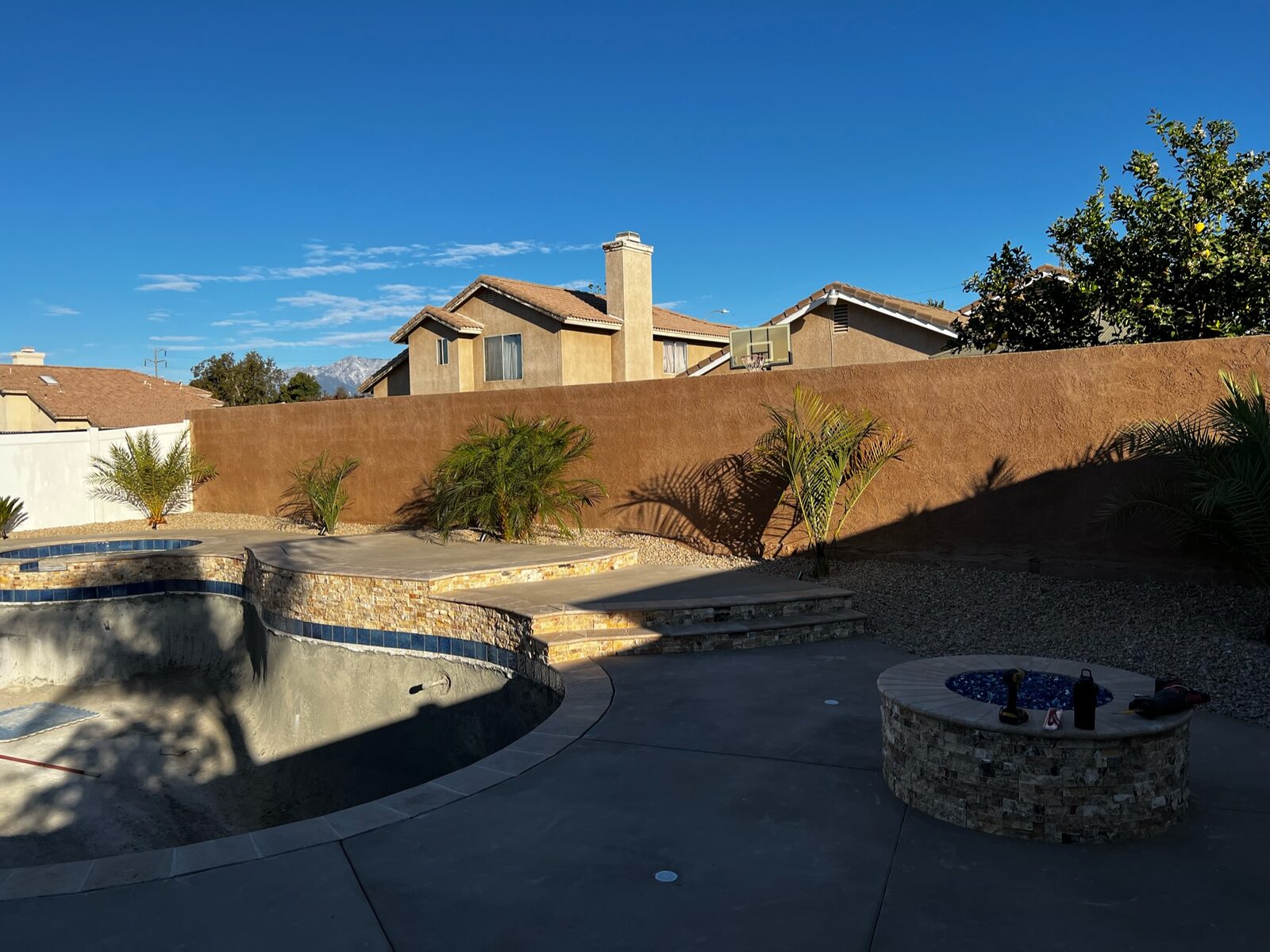 Pool remodel with stone accents and fire pit at sunset